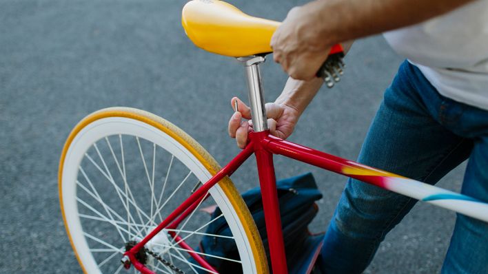 Ein Mann stellt die Sattelhöhe an seinem Fahrrad ein © IMAGO / Addictive Stock