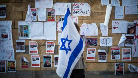 Eine Frau, die eine israelische Fahne hält, guckt sich Tel Aviv Plakate an, auf denen Personen zu sehen sind, die von der Hamas entführt wurden © dpa/Ilia Yefimovich
