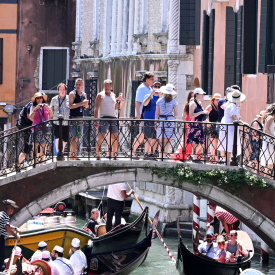 Tourist*innen gehen über eine Brücke in Venedig © IMAGO / Xinhua