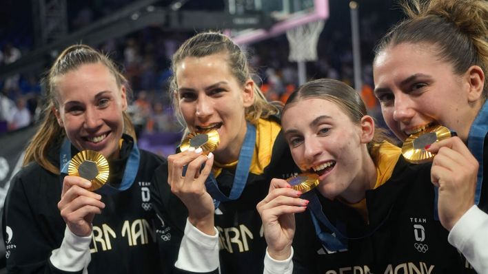 Svenja Brunckhorst (l-r), Sonja Greinacher, Elisa Mevius und Marie Reichert beißen nach der Siegerehrung auf ihre Goldmedaille © Maximilian Specht/dpa