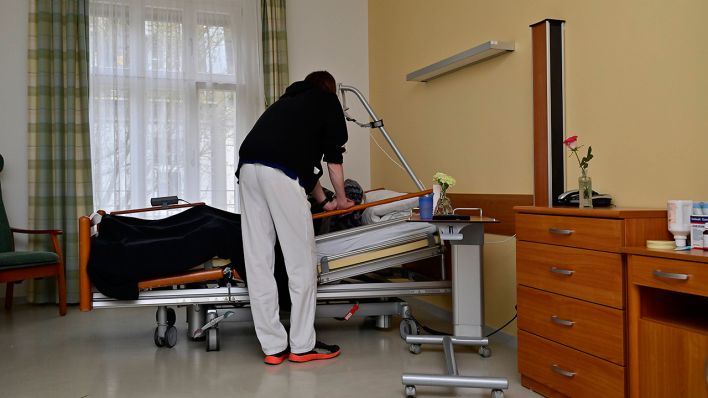 Ein Pfleger spricht mit einem Patienten in einem Hospizzimmer (Symbolbild) © imago images/Ralph Lueger