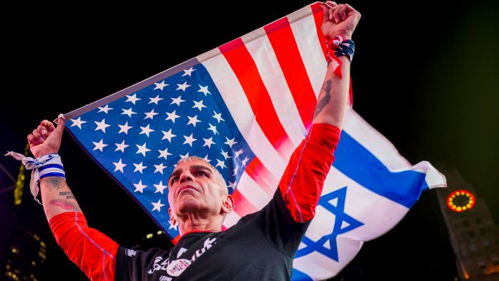 Ein Mann hält eine Flagge USA/Israel hoch (Foto:IMAGO / ZUMA Press Wire)