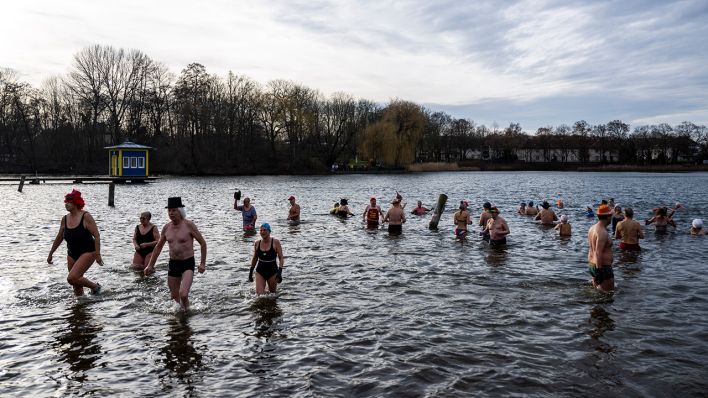 Menschen gehen beim Neujahrsbaden des Vereins Berliner Seehunde im Orankesee baden © picture alliance/dpa | Christophe Gateau