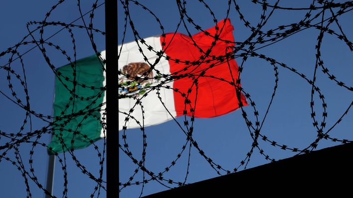 Flagge von Mexiko im Grenzgebiet zu den USA hinter Stacheldraht © IMAGO/Shotshop