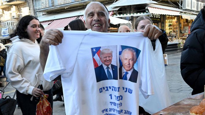 Mann in Jerusalem hält Trump/Netanyahu- T-Shirt vor die Kamera © IMAGO / UPI Photo